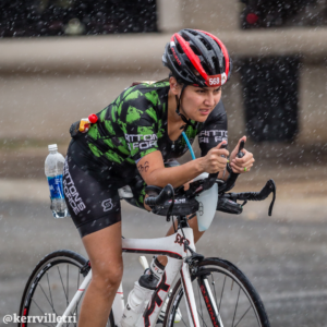 Cyclist rides during the rain with her hydration bottles visible during the Kerrville Triathlon. Credit Ed Sparks.