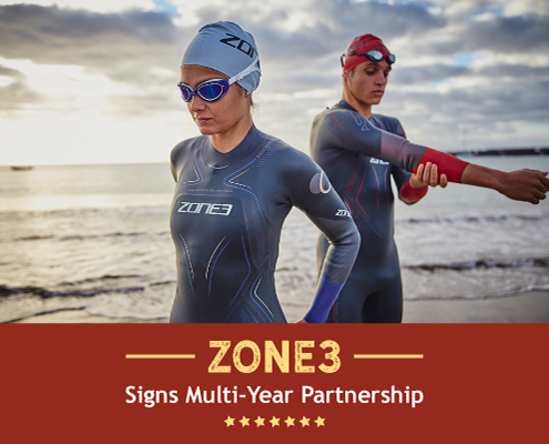 Two triathletes prepare for an open water swim in their Zone3 wetsuits. Text on design reads Zone3 Signs Multi-Years Partnership. Learn more at http://kvy.b5e.myftpupload.com/2021/05/zone3-usa-partnership/